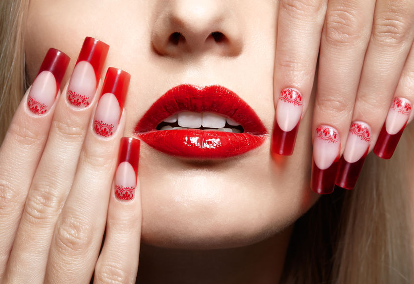 Fingers with red french acrylic nails manicure and paiting